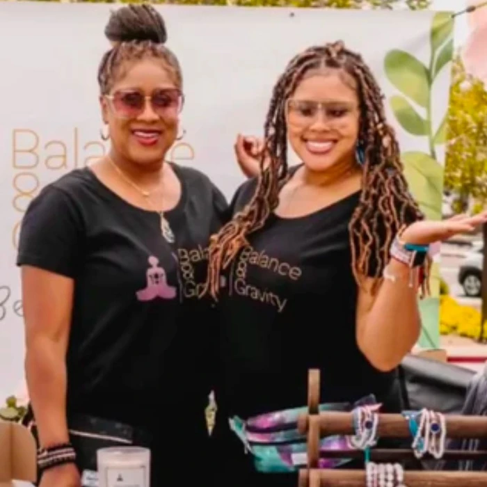 Mother-daughter team smiles together, promoting holistic products at their booth for metaphysical healing treasures.