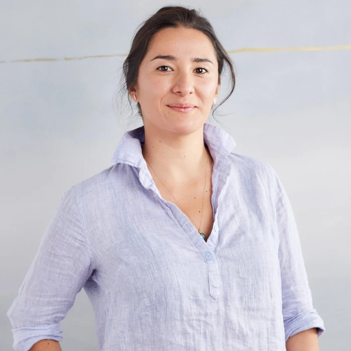 Chef Michelle Minori smiles confidently in a casual shirt, showcasing her culinary expertise and vibrant personality.