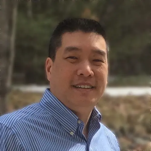 Smiling man in a blue shirt outdoors, showcasing his passion for education and culinary arts.