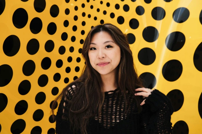 Host profile photo: a smiling individual in front of a vibrant yellow and black polka dot backdrop. Passionate about pottery.