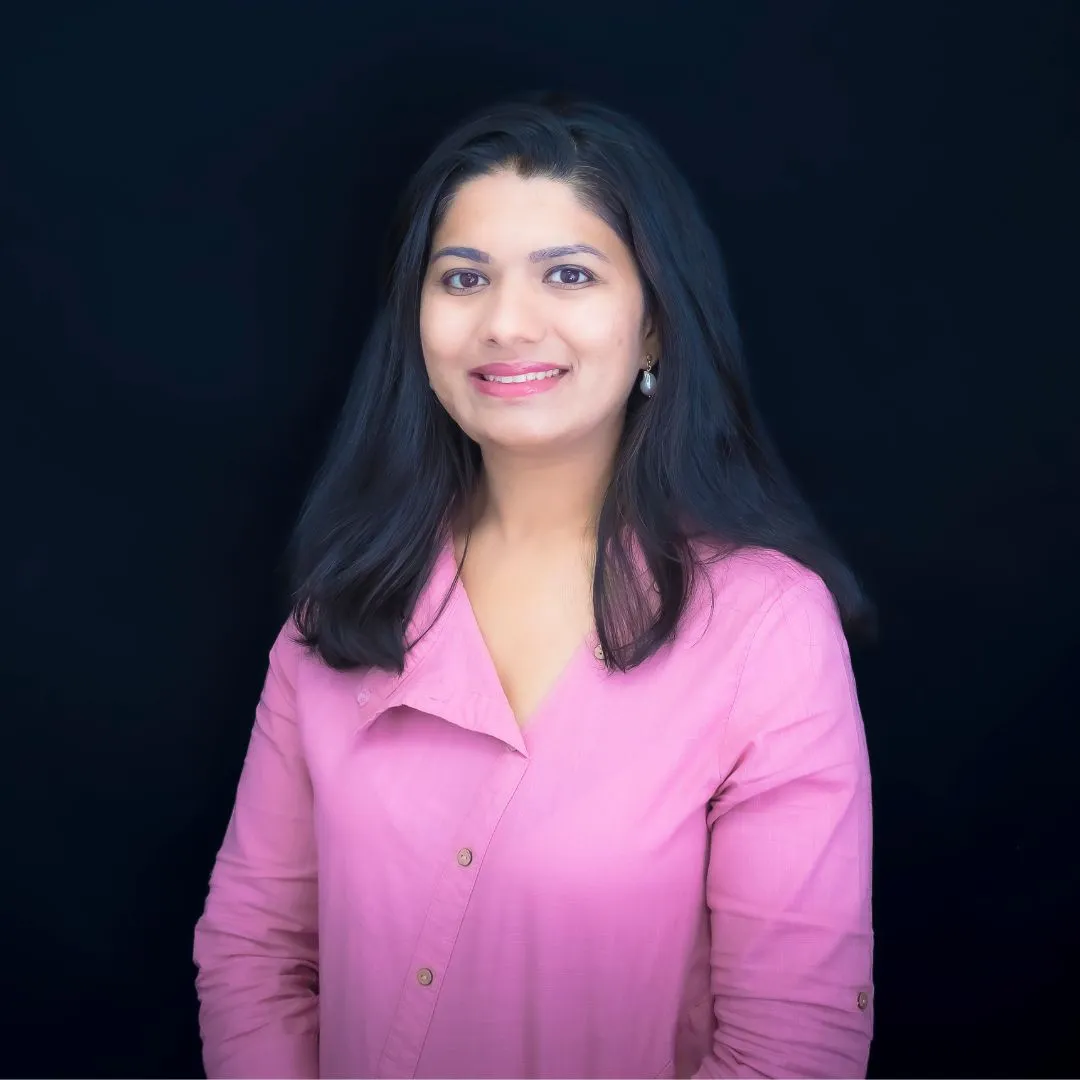 A smiling person in a pink shirt stands against a black background, embodying confidence and self-acceptance.