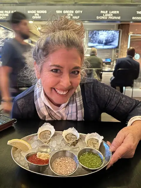 Denise Righetti smiles with a platter of oysters and condiments, ready to share her culinary passion.