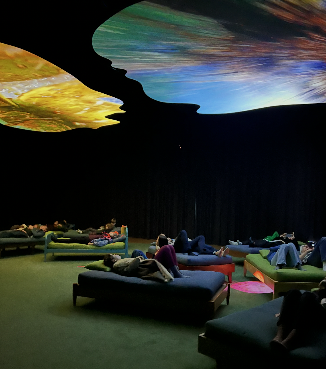 Visitors reclining beneath overhead digital projection screens at the Portland Art Museum