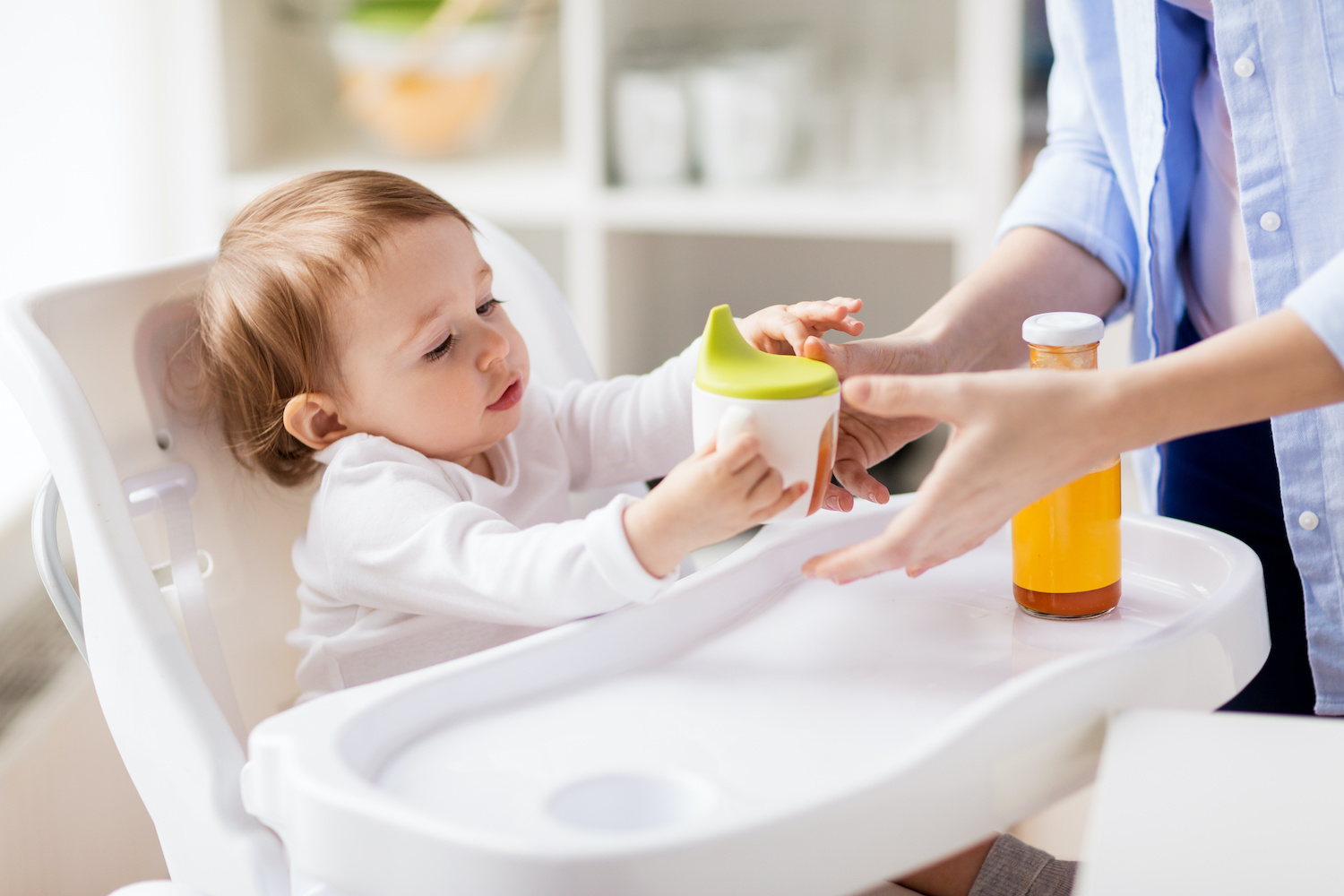 Child with sippy cup in high chair