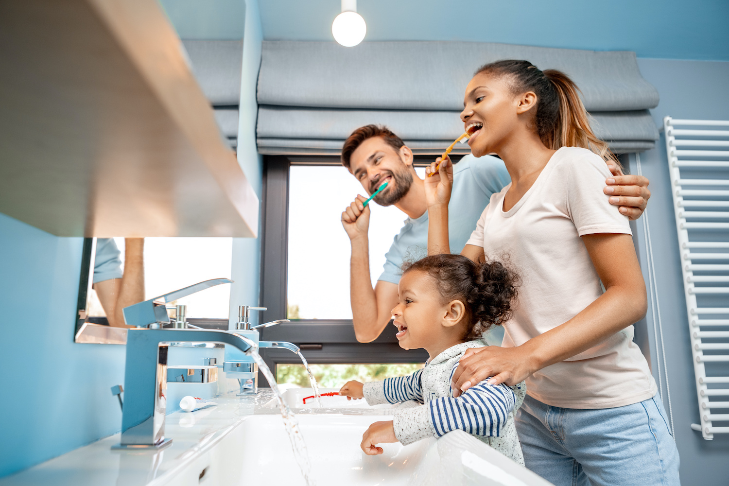 parents brushing their teeth with their child in the bathroom
