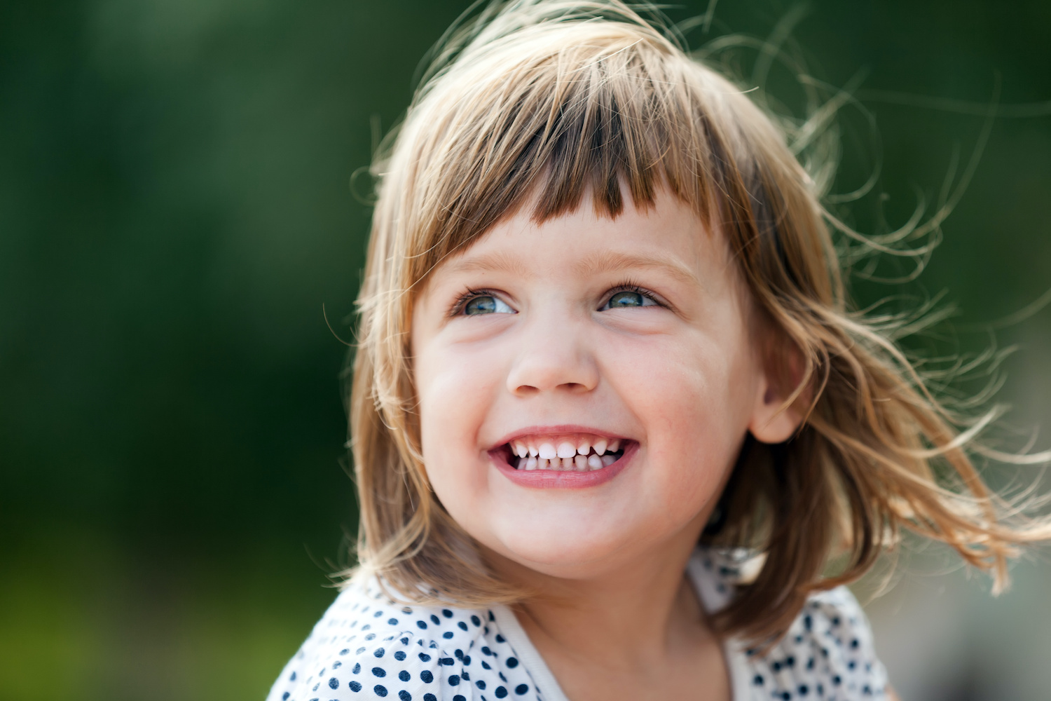 little girl smiling outside with wind in her hair