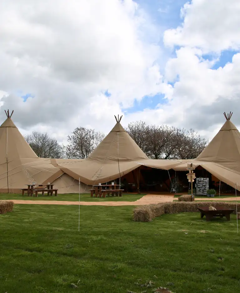 Three Giant Tipi setup with a walk way and firepit