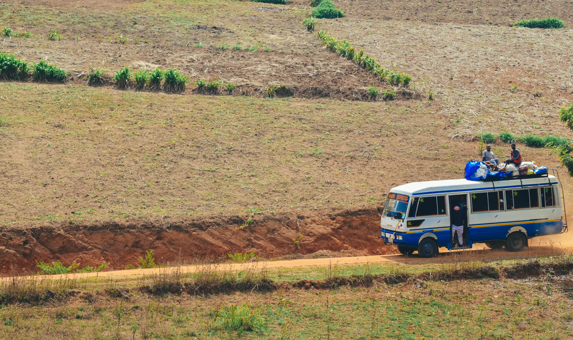 A rural passenger bus loaded with cargo travels a remote dirt road, where 2G coverage thins out first.