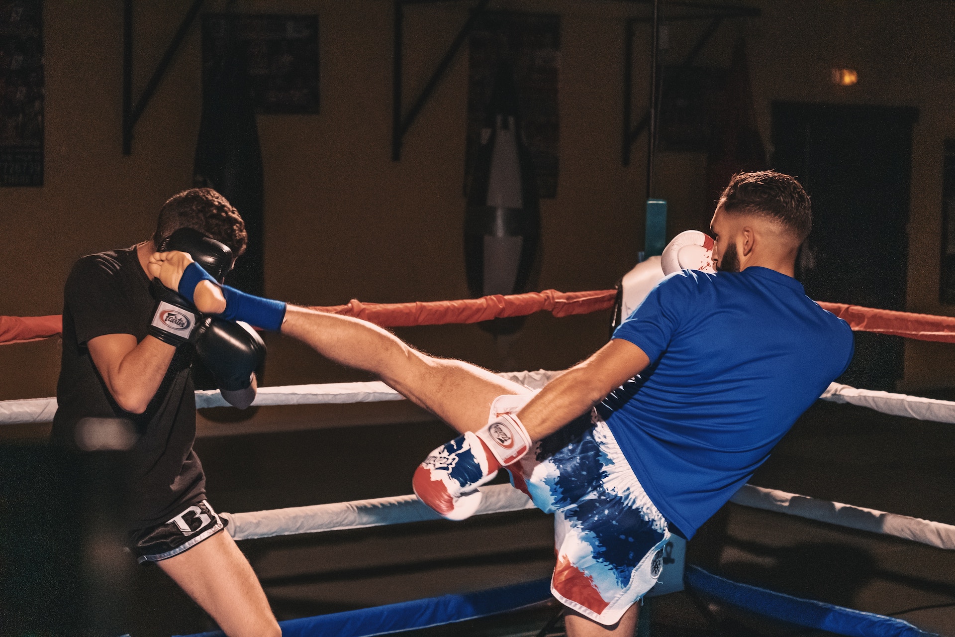 Deux Boxeur sur un ring, l'un des deux donne un coup de pied à l'autre
