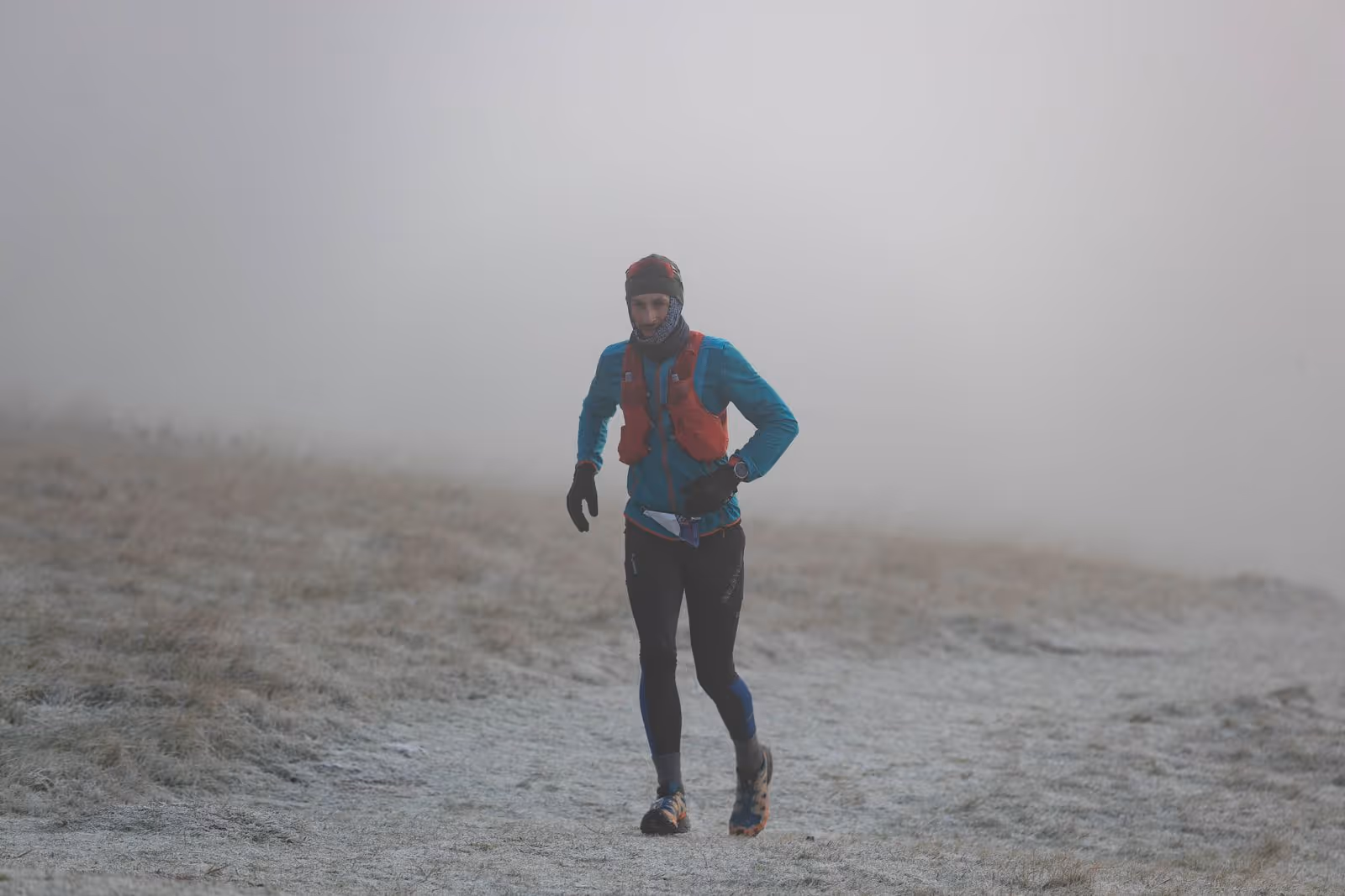 A person in athletic gear is smiling while running outdoors with a race number 95 on.