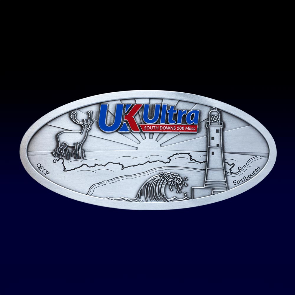Silver oval medal with "UK Ultra" text, featuring a deer, wave, and lighthouse design.
