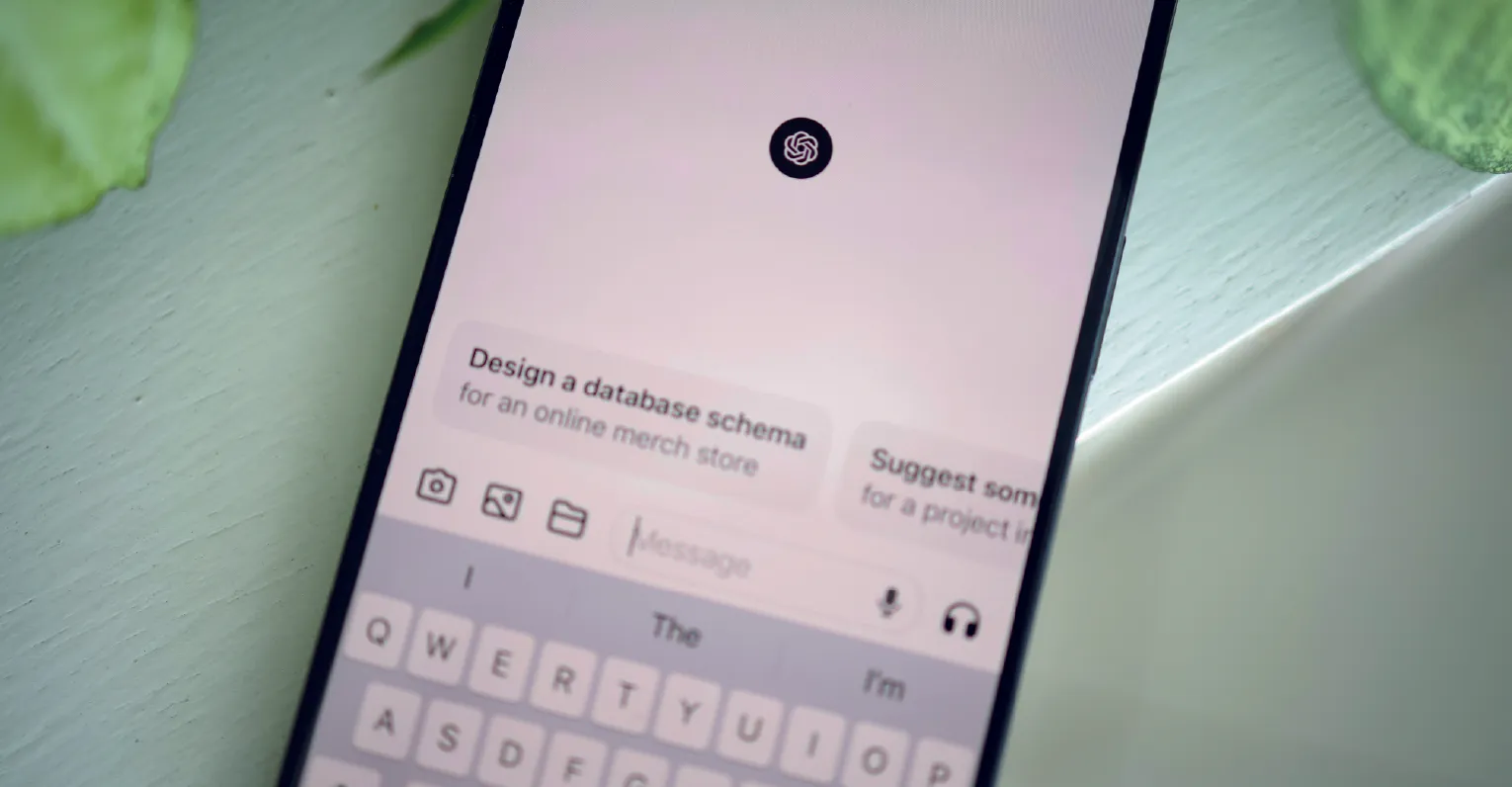 Teléfono celular apoyado sobre un fundo verde, que en su pantalla muestra el inicio de una conversación en ChatGPT.