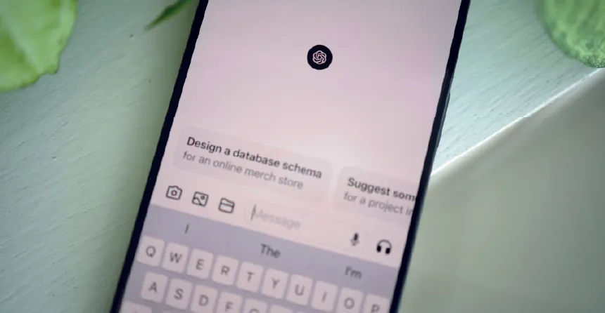 Teléfono celular apoyado sobre un fundo verde, que en su pantalla muestra el inicio de una conversación en ChatGPT.