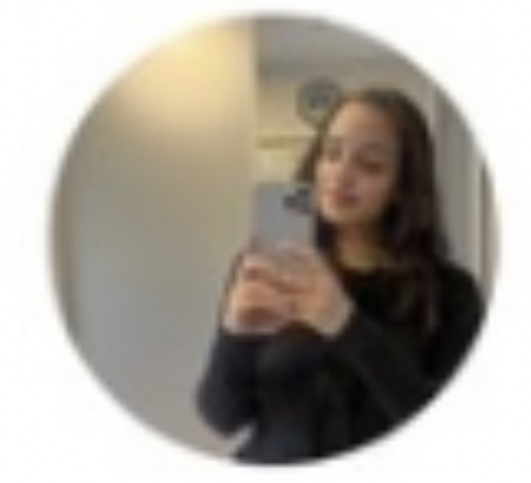 Woman with long hair wearing black taking a mirror selfie with a smartphone.