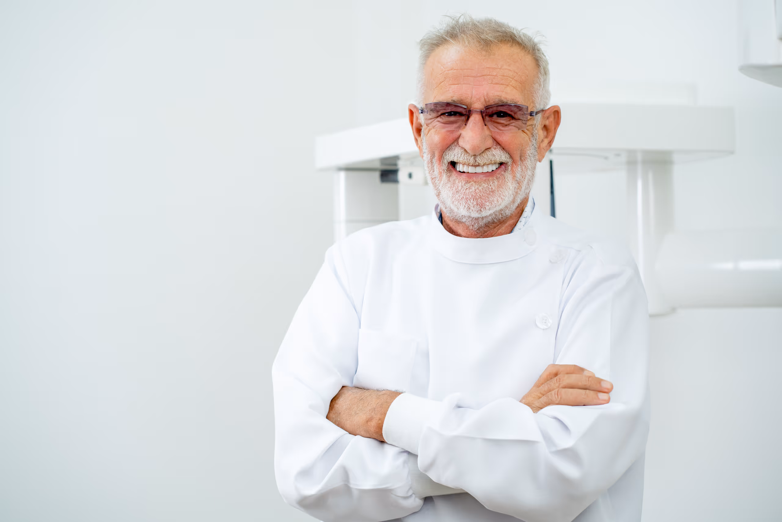 Smiling elderly professional in white uniform with crossed arms