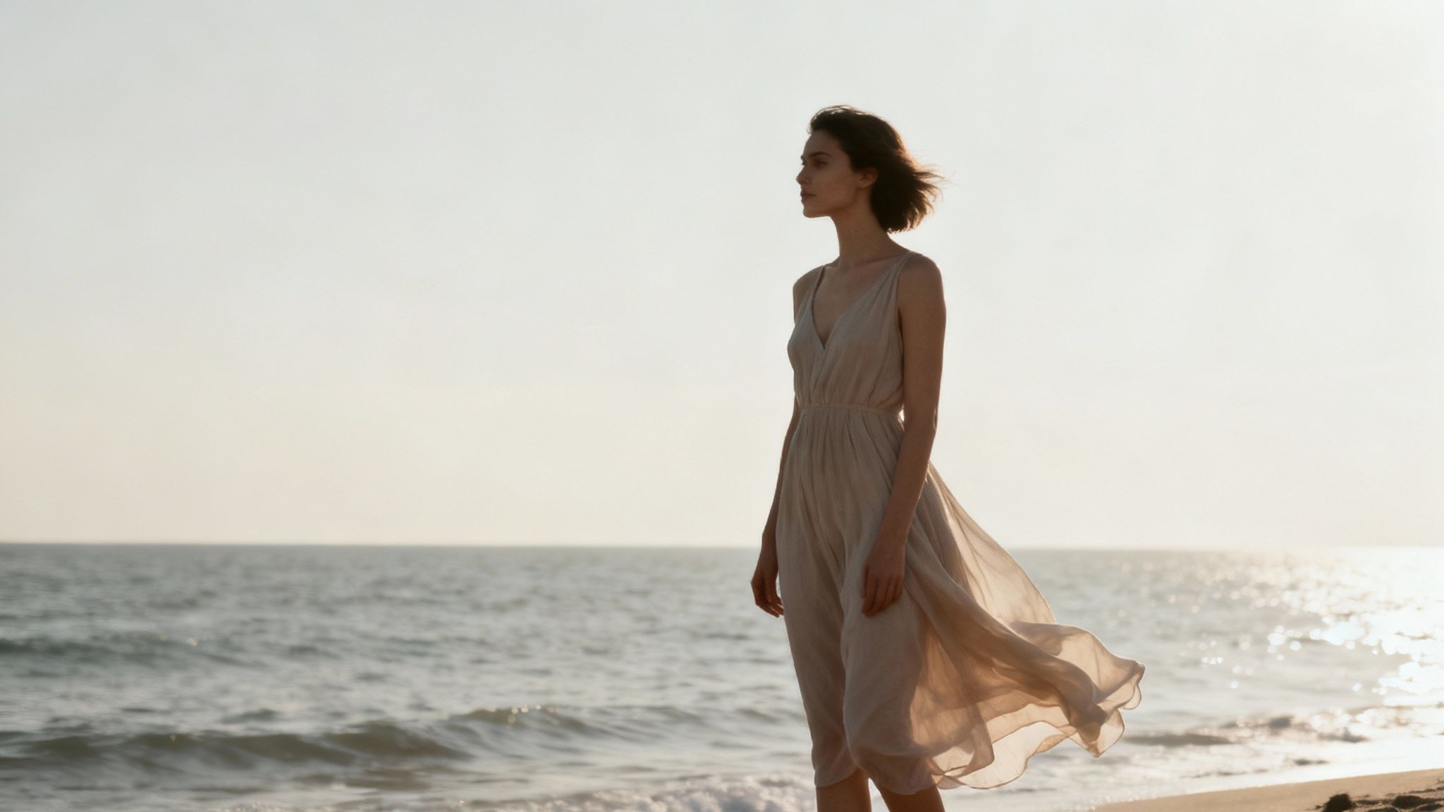 A model in a vibrant orange dress poses against a neutral, textured background for a professional photoshoot.