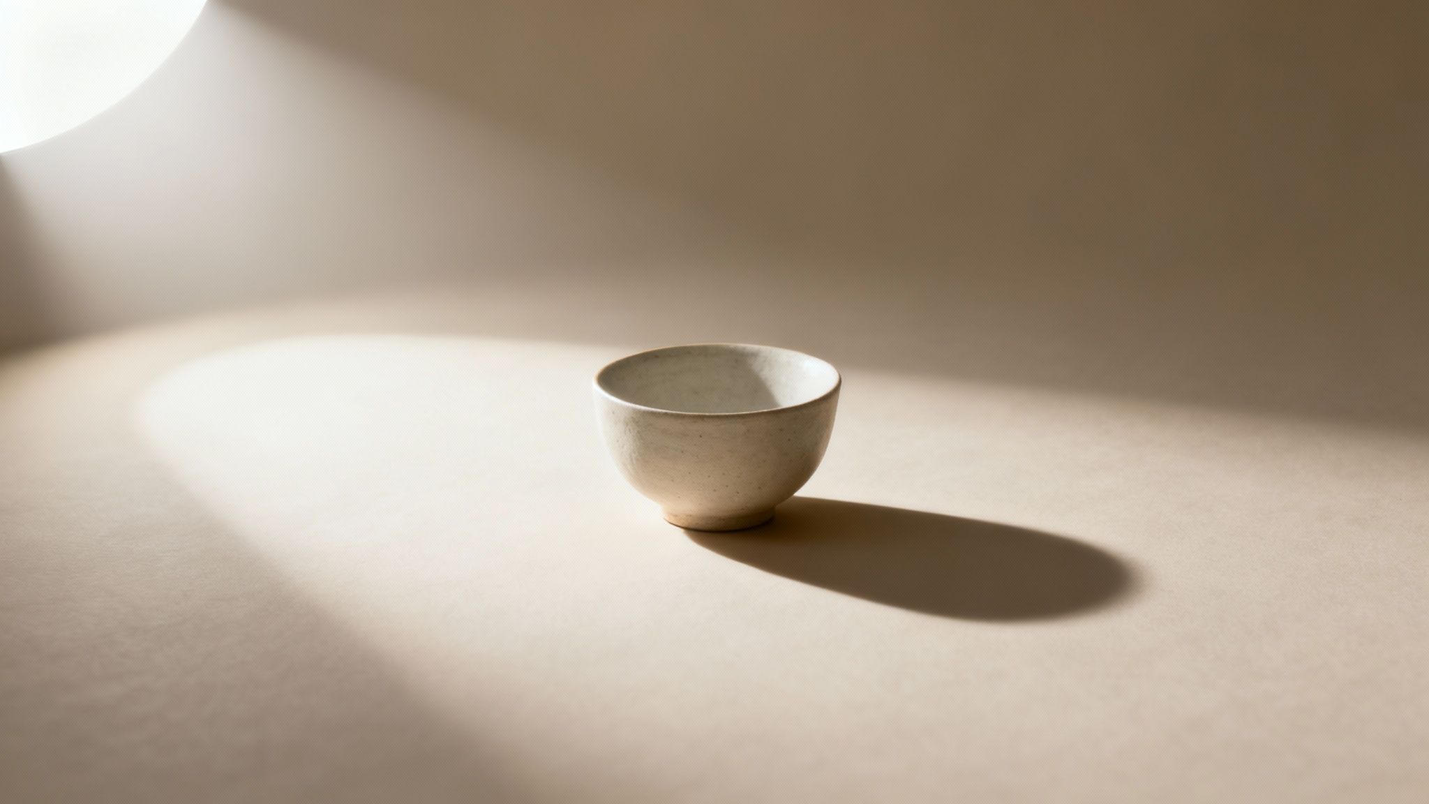 Minimalist ceramic bowl with soft shadow on neutral beige surface with natural lighting