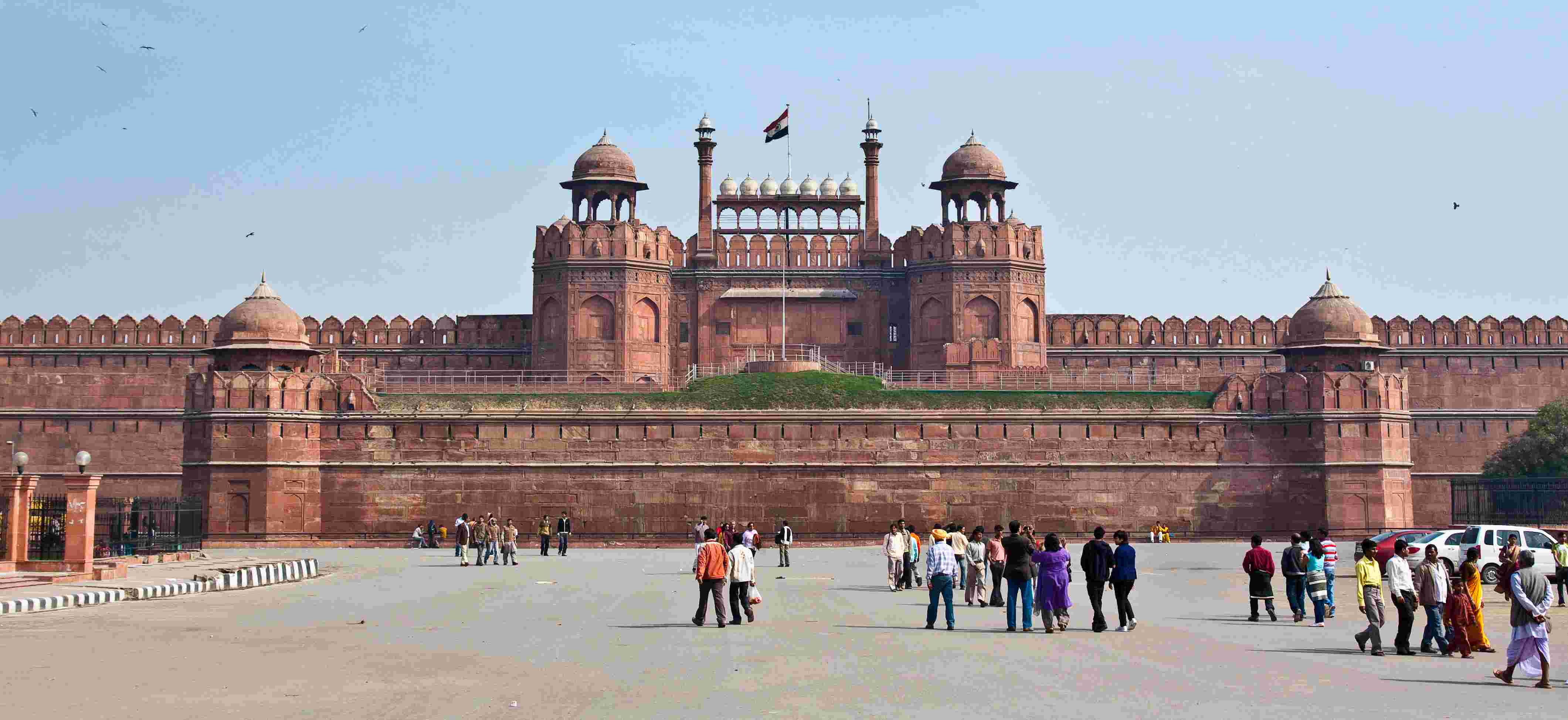 Visitors walking in front of the Red Fort in Delhi with the Indian flag flying atop its main gate.