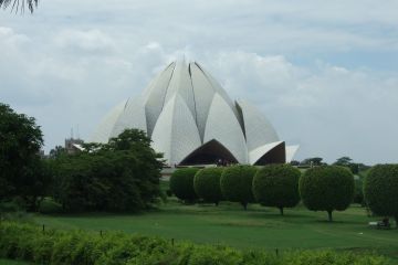 The Lotus Temple in Delhi, an architectural structure shaped like a white blooming lotus flower surrounded by greenery.