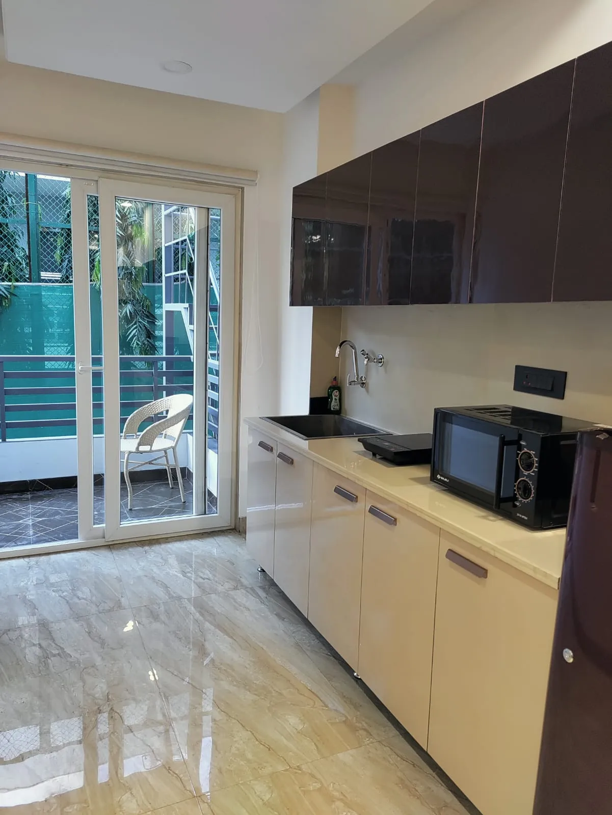 View of the kitchen area in the studio with the balcony at the back for the convenience of the guests coming to DLF Cyber city