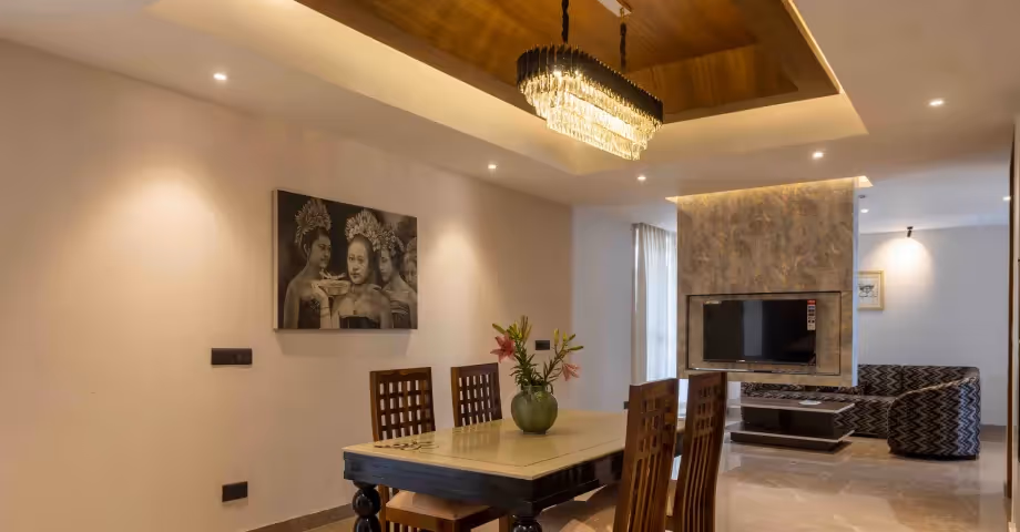 Dining area at 2BHK in Casa Feliz with a modern wooden dining table, chairs, and warm lighting – ideal for families and group stays.