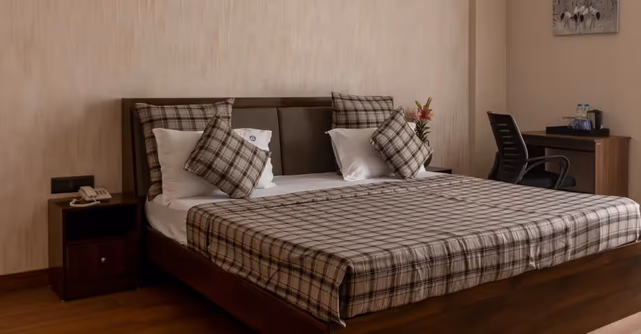 Comfortable bedroom in 2BHK in Casa Feliz featuring a checkered bedspread, cozy lighting, and inviting interiors – ideal for business travellers or families.