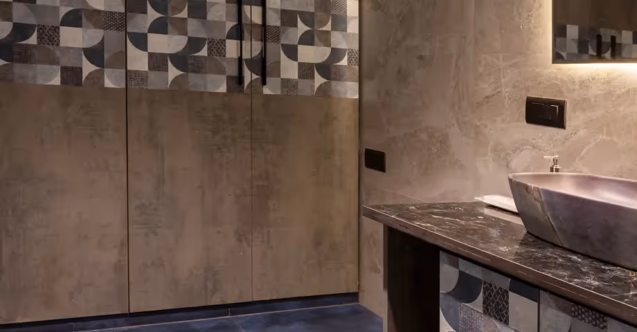 Modern bathroom at 2BHK in Casa Feliz featuring a glass shower enclosure, round mirror, and elegant stone sink.