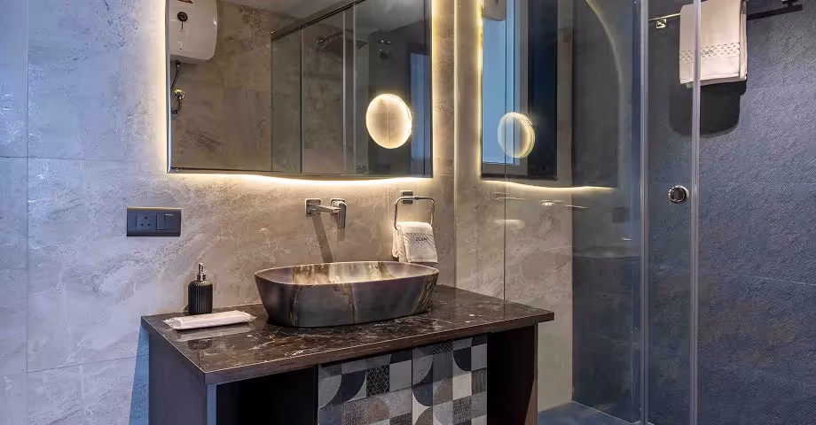 Modern bathroom at Casa Feliz luxury room with common balcony, featuring sleek vanity, stone sink, and glass shower area."