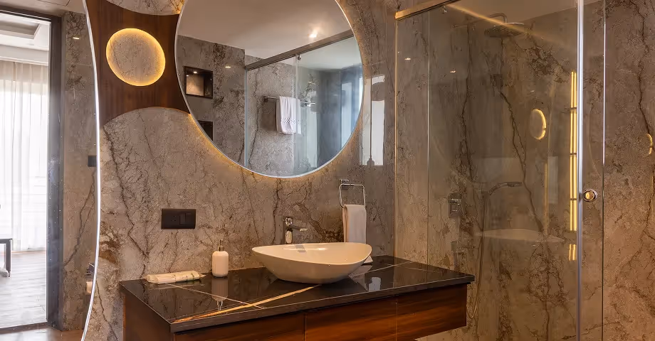 Stylish bathroom at 2BHK in Casa Feliz with wooden vanity, round mirror, and high-end fittings.