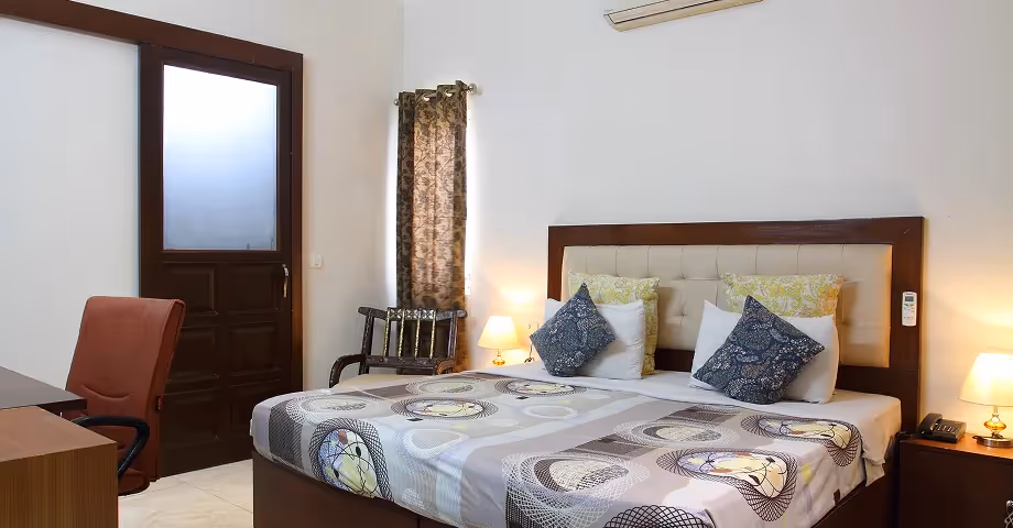 Classic Room in Sushant Lok with a comfortable queen bed, seating area, and large window overlooking greenery also features a work desk – ideal for business travellers or families