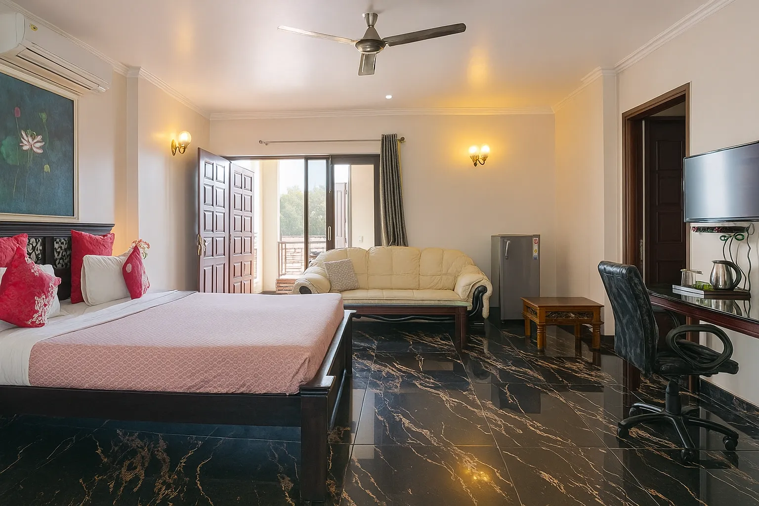 Spacious bedroom at Sterling Studio Apartment in Sushant Lok with large bed, seating area, and natural light from wide windows – ideal for business travellers or families.