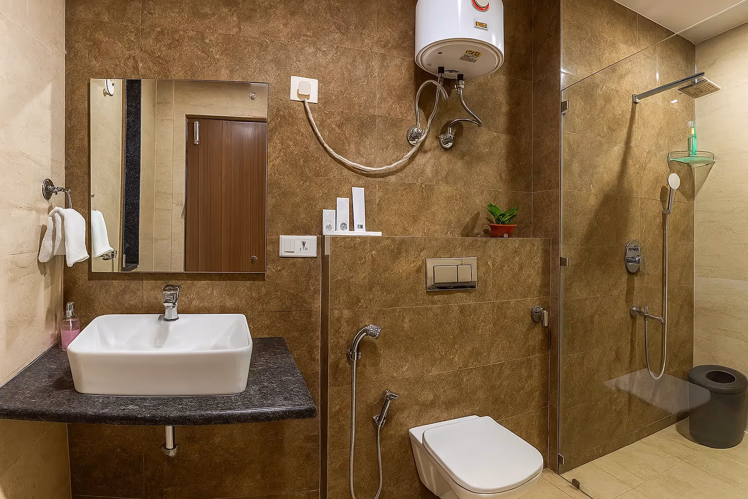 Modern bathroom at Sterling Room in Cyber City with western toilet, clean wash basin, and wall-mounted shower.