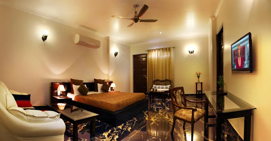 Dining area at Sterling Studio Apartment in Sushant Lok with a wooden dining table, chairs, and cozy lighting – ideal for business travellers or families.