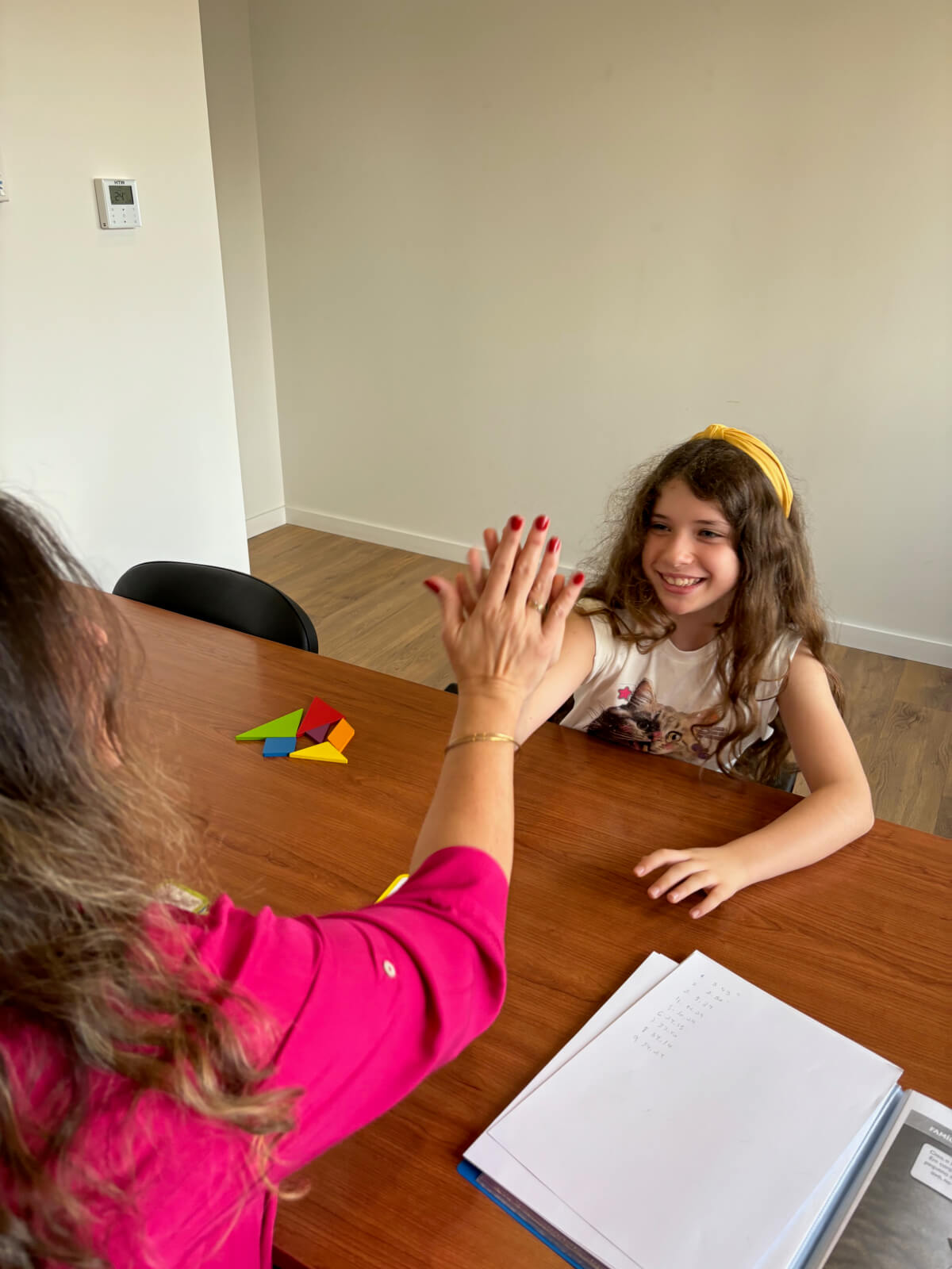 Sessão de Psicologia Clínica para crianças com paciente e psicologa sentadas em numa secretária entre jogos.
