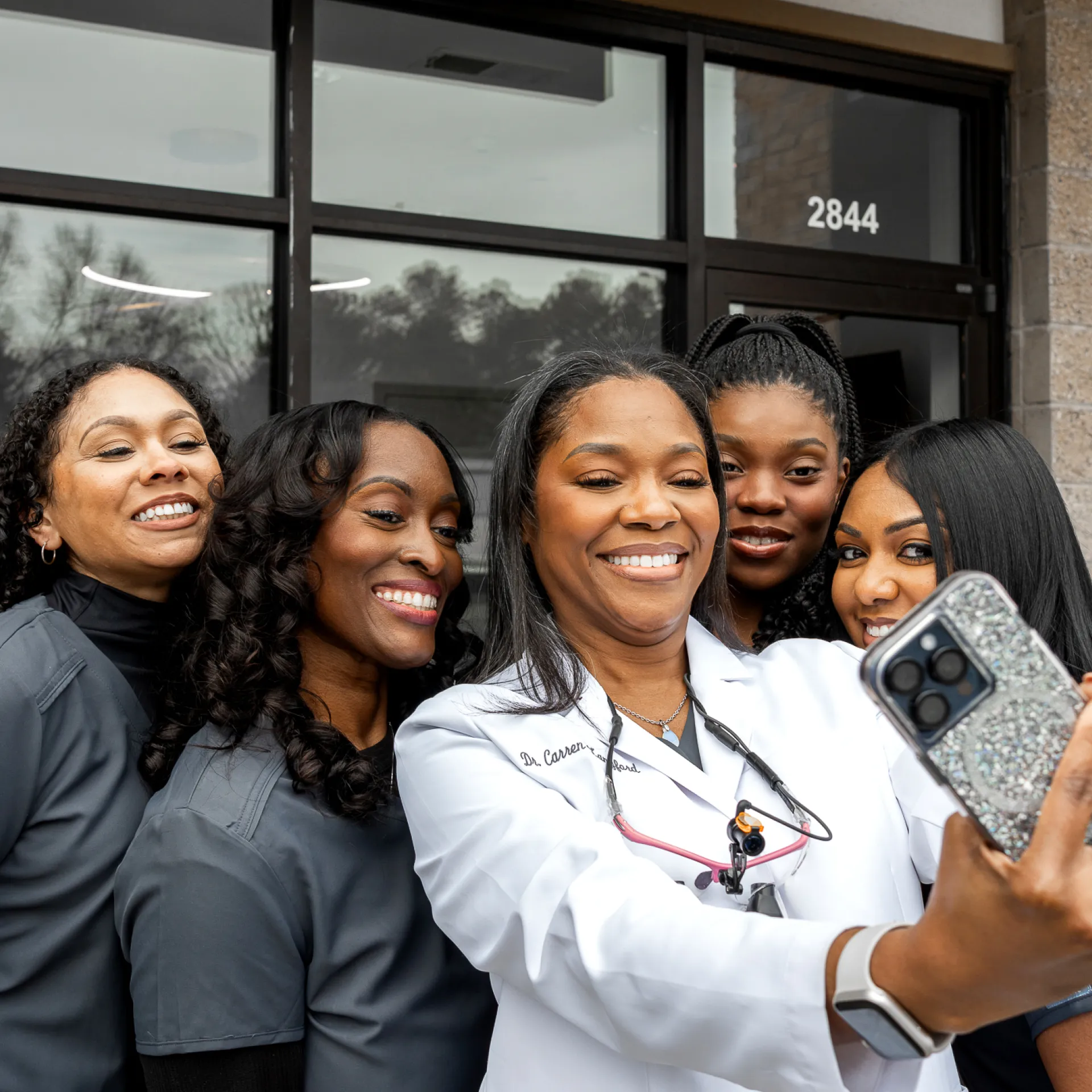 A group of women taking a picture with a cell phone.