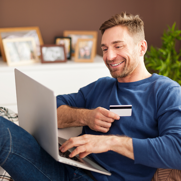 Homme effectuant un paiement en ligne sur son ordinateur avec une carte bancaire, illustrant la sécurité et la confidentialité des démarches de prêt en ligne.