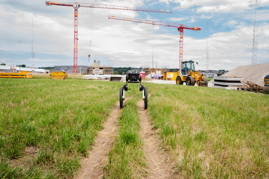Ascento Guard security robot autonomously patrolling rough terrain at a construction site.