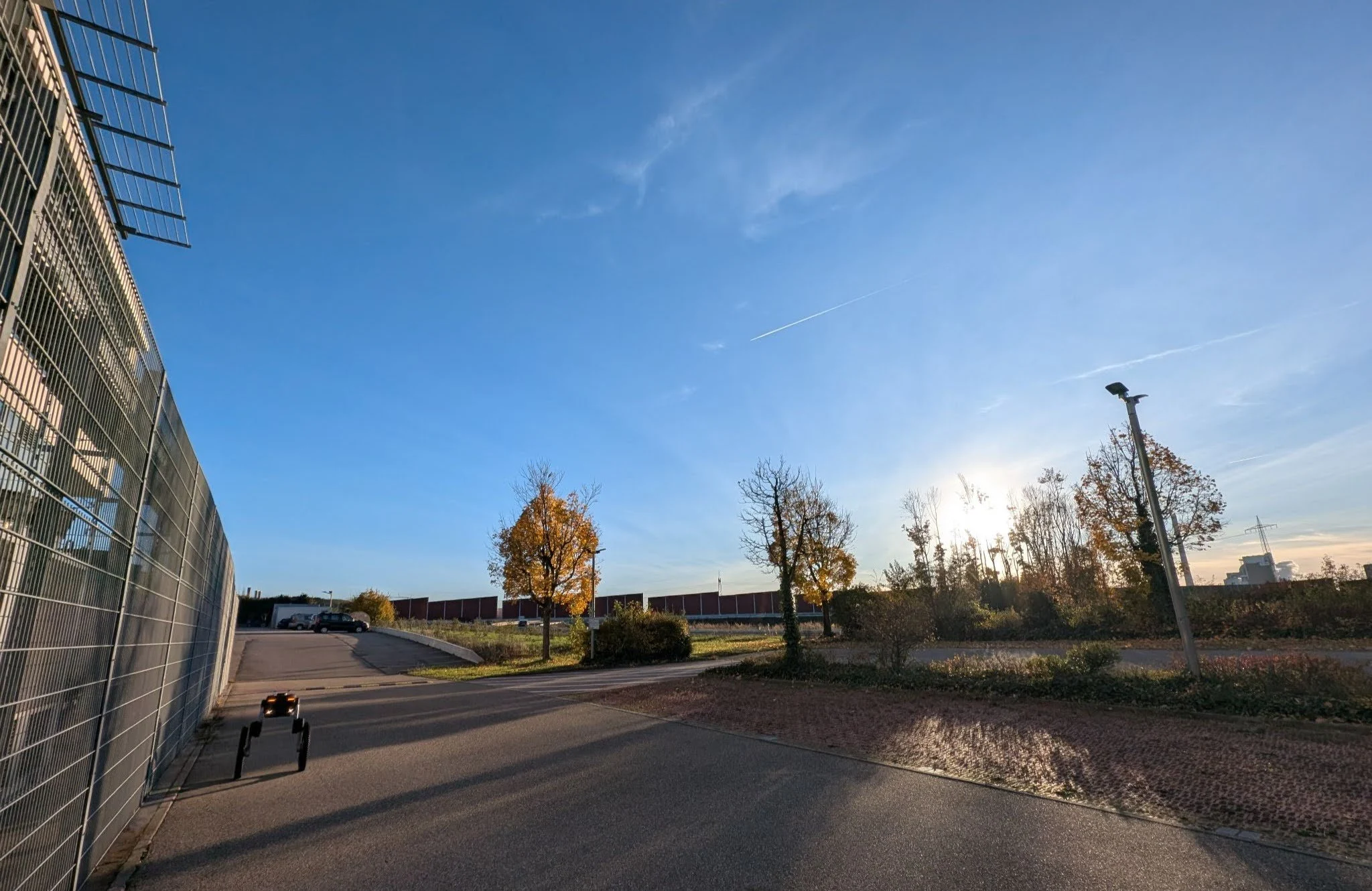 Autonomous security robot patrolling an industrial facility perimeter at sunset.