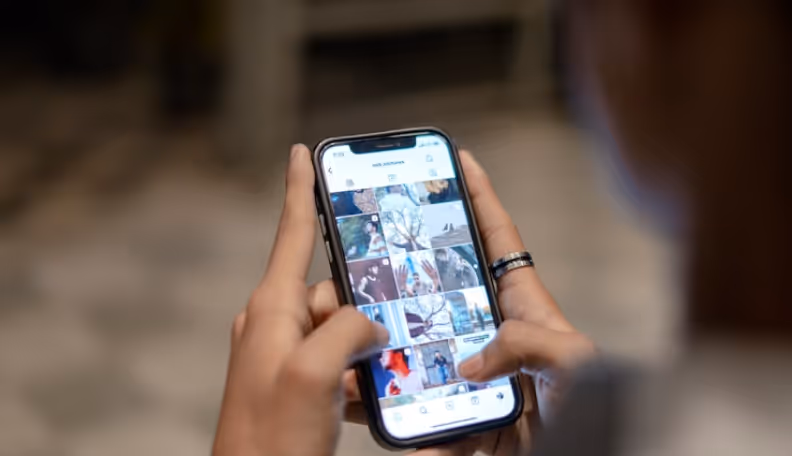 Person scrolling through a photo gallery on a smartphone held with both hands.