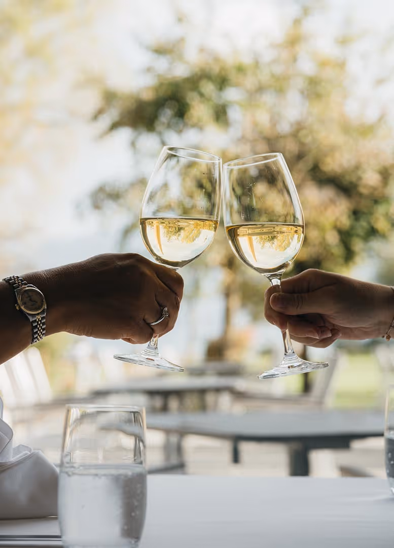 Zwei Personen stossen mit Wein im Restaurant Delta am Thunersee an