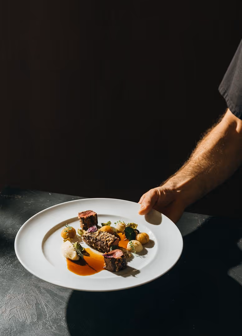 Fleischgericht des Hotelrestaurants wird vom Koch präsentiert