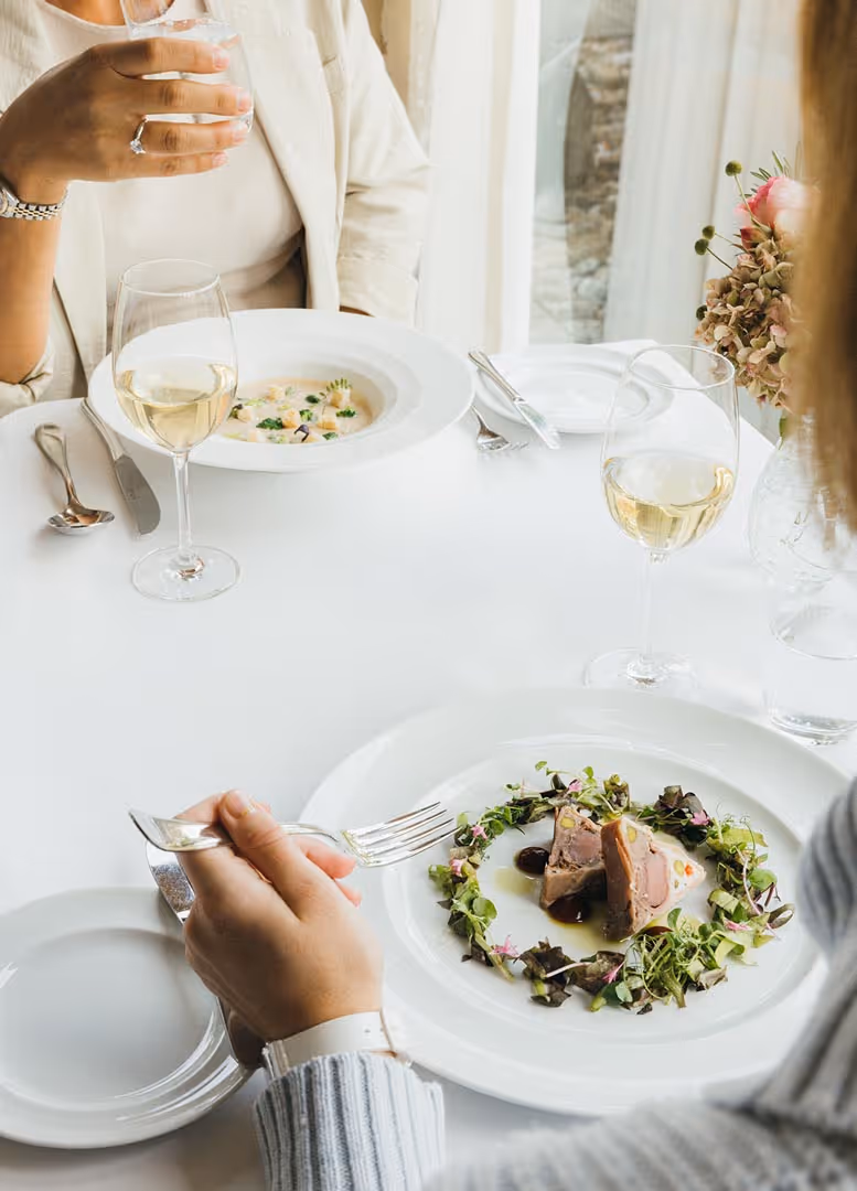 Zwei Damen sitzen am Tisch mit zwei verschiedenen Gerichten und dem passenden Wein