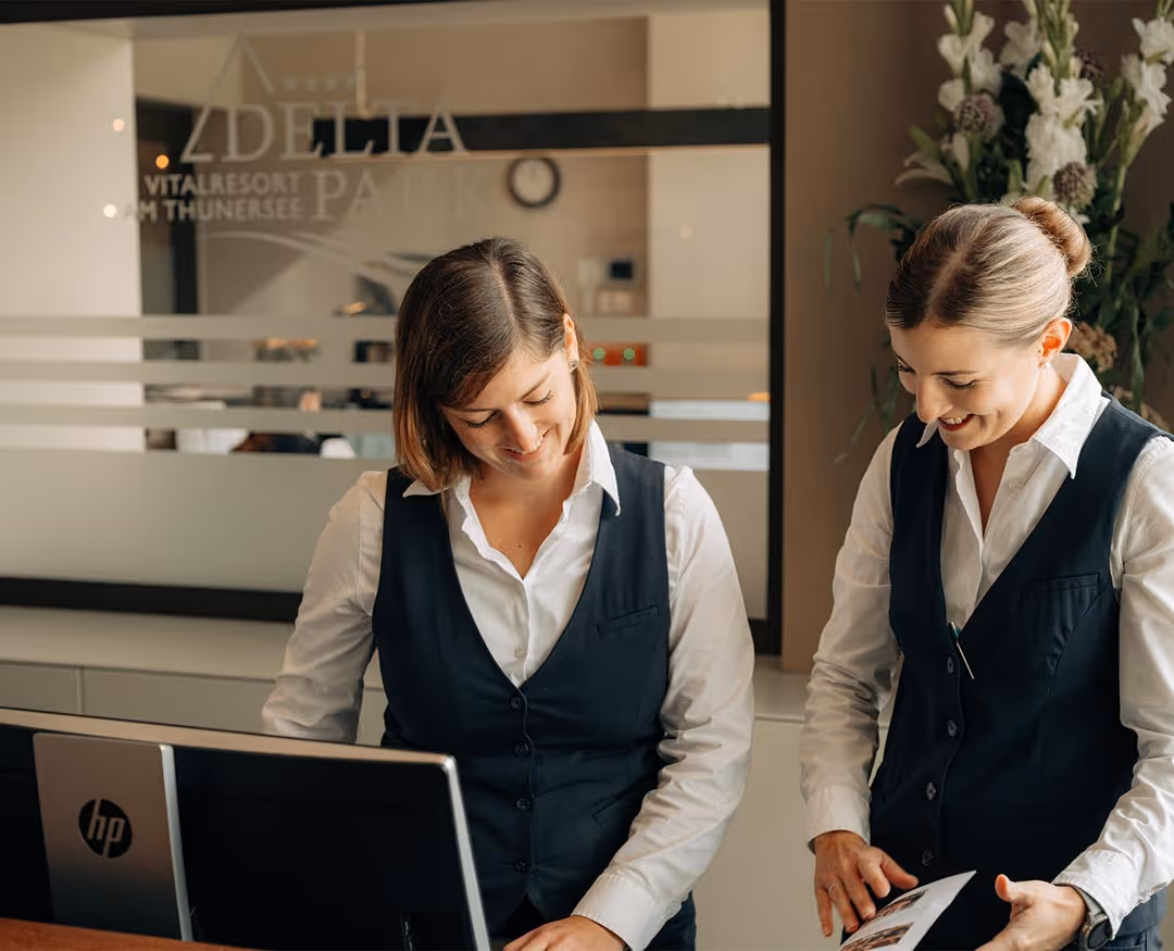 Two receptionists work together at the reception desk