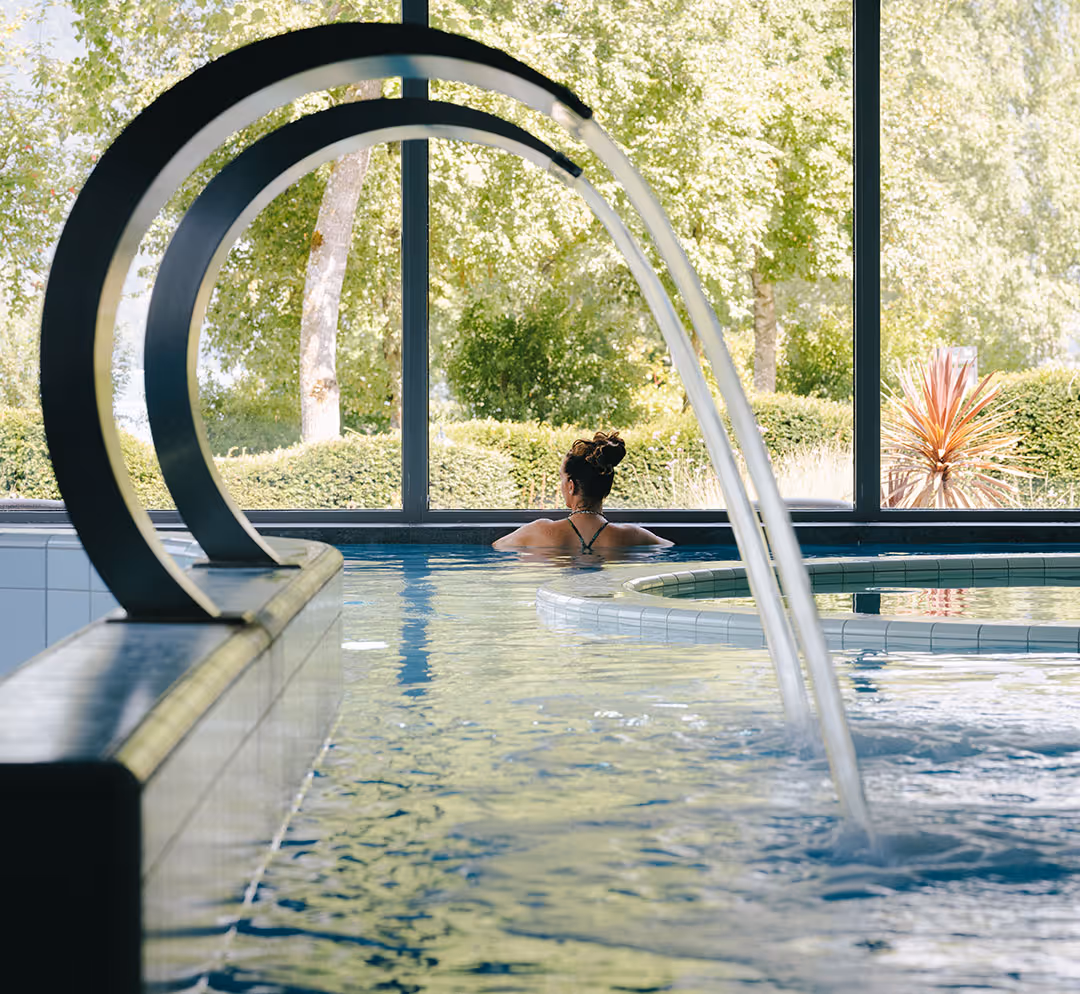 Dame im Indoor-Solepool mit Aussicht ins Grüne im Deltapark Vitalresort