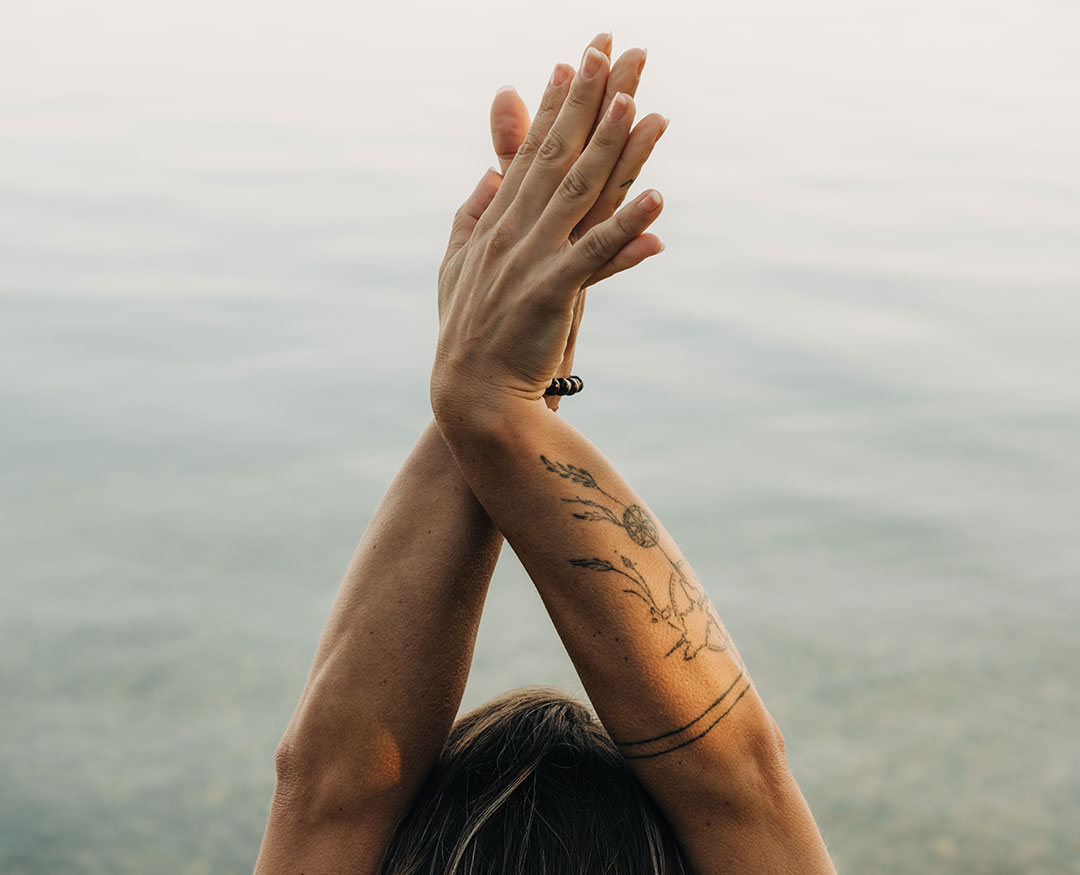 Lady in yoga pose directly on the shore of Lake Thun at the Deltapark Vitalresort