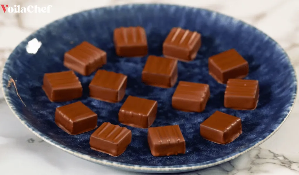 Carrés de chocolat garnis de ganache lisse et onctueuse sur une assiette