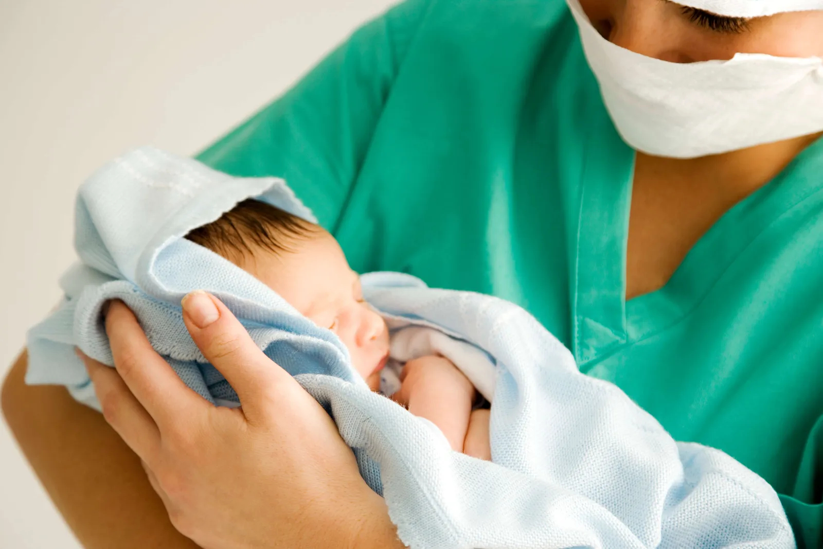 Nurse holding a newborn baby wrapped in a blanket