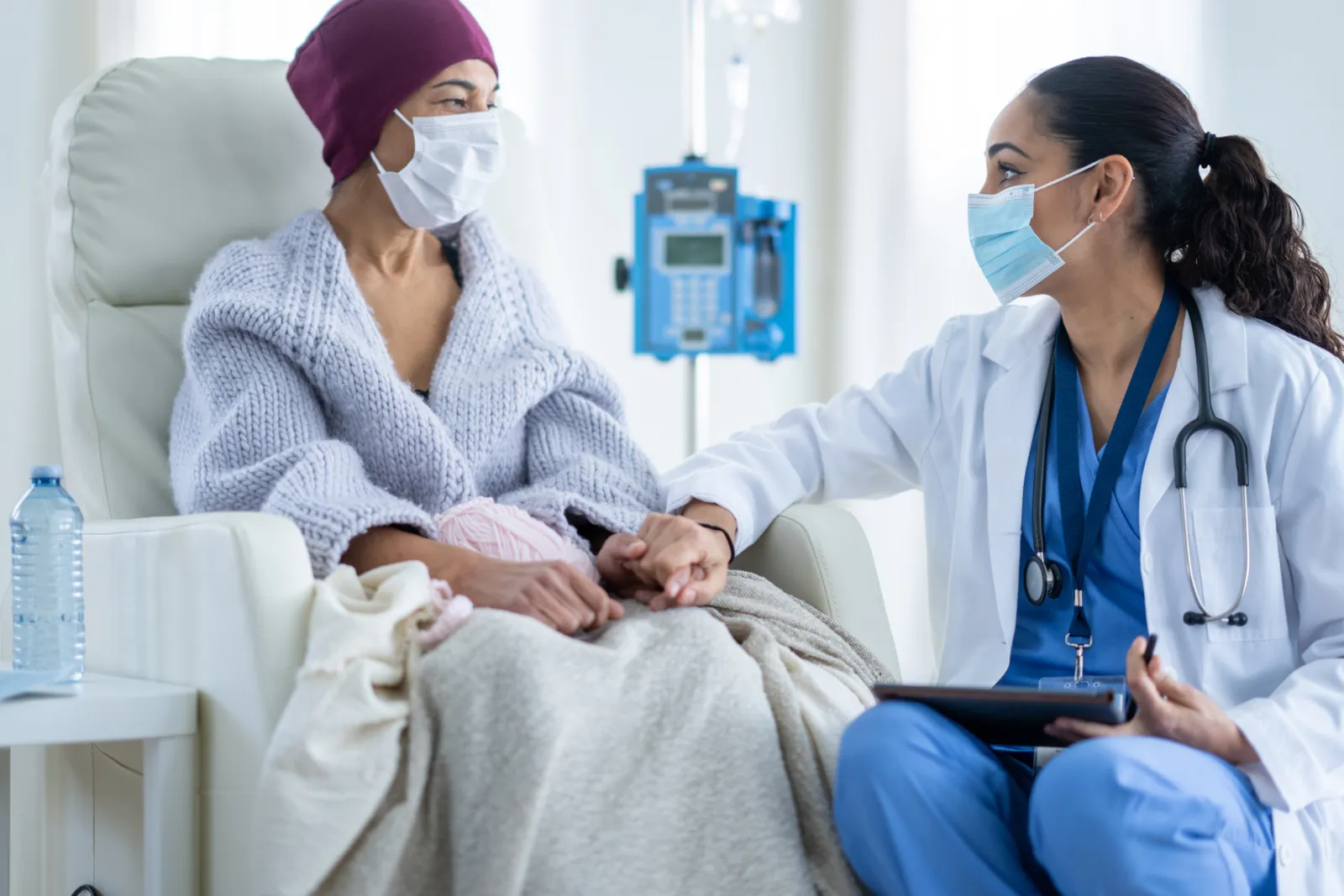 Oncology nurse holding hands with a patient during infusion treatment