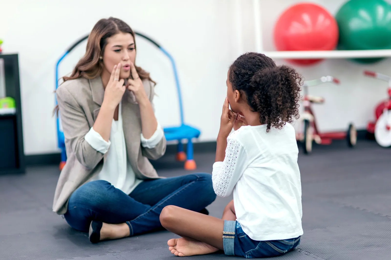 Speech therapist and a young girl practicing sounds together