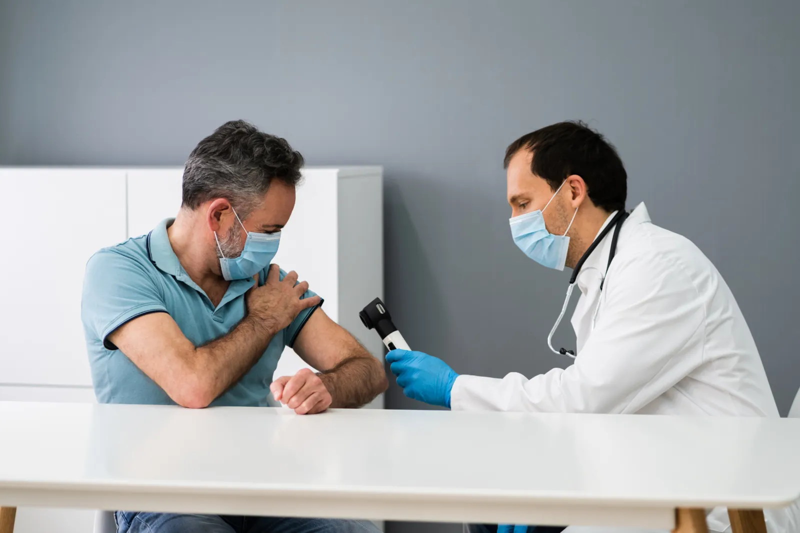 Dermatologist examining a patient's shoulder with a dermatoscope